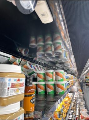 Wireless temperature sensor mounted on a refrigerated shelf unit